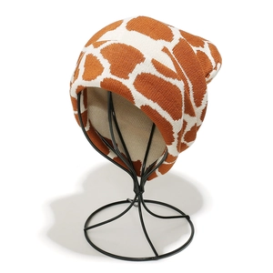 Winter knitted beanie featuring brown and white giraffe jacquard pattern on a metal stand