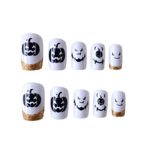 Faux ongles Halloween avec sourires de citrouille noirs et paillettes dorées