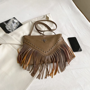 Sac bandoulière marron à franges avec clous et croix dans un décor lifestyle