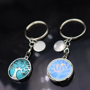 Tree of Life keychains with turquoise and opal stones on a black reflective background