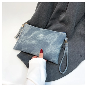 Detail of blue-gray marble textured clutch with wristlet strap and stylish tassel charm