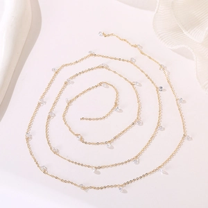 Macro detail of a gold thin chain necklace with transparent teardrop zircon pendants