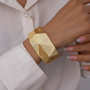 Detailansicht der facettierten goldenen geometrischen Manschette mit Sonnenstrahl-Textur