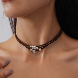 Close-up of layered coffee leather choker with silver heart pendant and metal beads