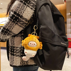 Plush cat charm wearing fish costume on a black backpack with golden keychain
