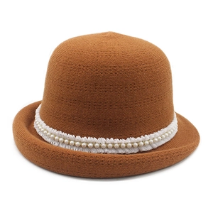 Close-up of caramel knit cloche hat with white lace trim and faux pearl accents