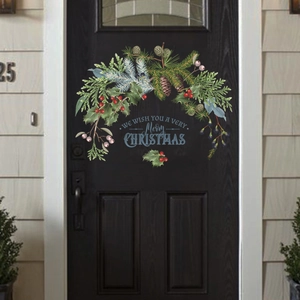 Detail of a Christmas wreath sticker with pine cones and festive text on a dark front door