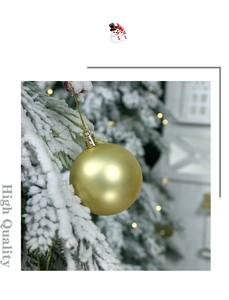 Close-up of matte golden Christmas ball hanging on a snowy pine branch with lights