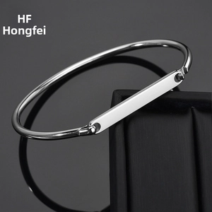 Polished silver stainless steel bangle with a minimalist rectangular plate on jewelry box