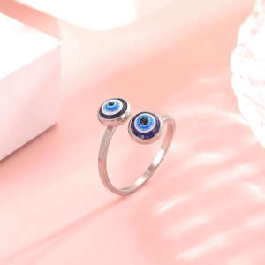 Macro view of evil eye charms on an adjustable silver ring with striped light shadows