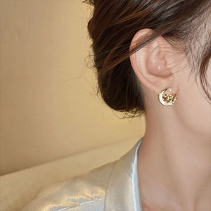 Elegant gold moon earrings with resin inlay and star charms worn by a female model