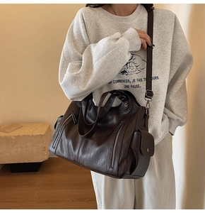 Detail of dark brown vintage leather tote bag with rivets shown on a female model