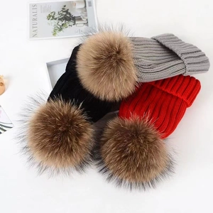 Detail of multi-color thick knit beanies with fluffy faux fur pom-poms for winter