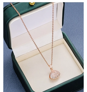 Close-up of 18k rose gold shell pendant with sparkling zircons in a green velvet jewelry box