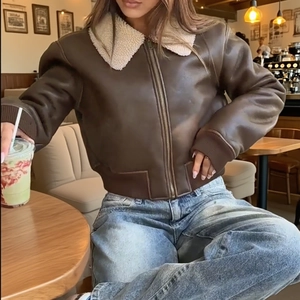 Detailed close-up of brown PU leather jacket with white faux shearling collar and zipper