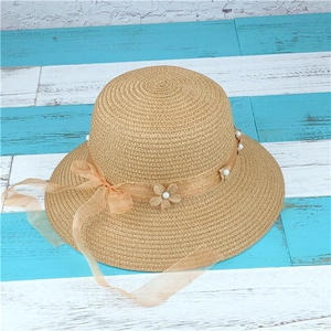 Detail of beige woven straw hat with light orange ribbon and pearl flower accents