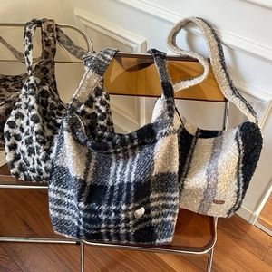 Detail of plush faux fur leopard and checkered tote bags arranged on a stylish chair