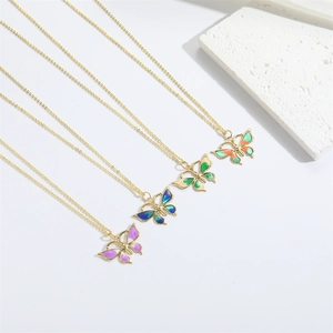 Set of four gold butterfly necklaces with colorful gradient enamel pendants on white background