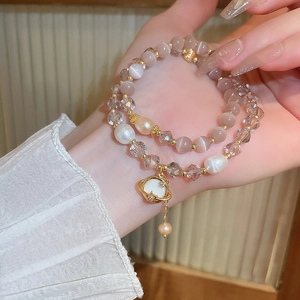 Détail d'un bracelet double rang avec perles d'eau douce, pierres œil de chat et pendentif planète