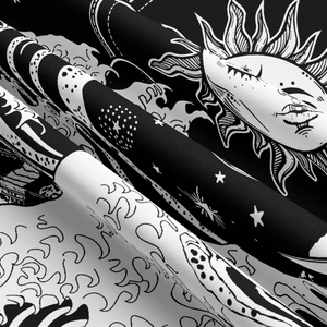 Detailed close-up of celestial sun and moon patterns on a black and white tapestry fabric