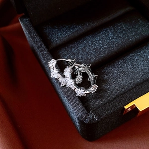 Vue détaillée des boucles d'oreilles fleur en argent et zircon sur velours noir