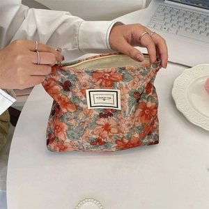 Detailed macro view of orange floral corduroy makeup bag with smooth metal zipper