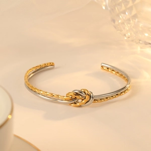 Two-tone heart knot bangle in gold and silver stainless steel with twisted texture