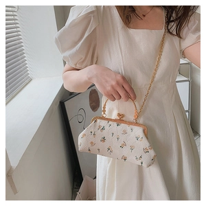 Detail of floral embroidery on vintage cream shell bag with golden metal frame and chain