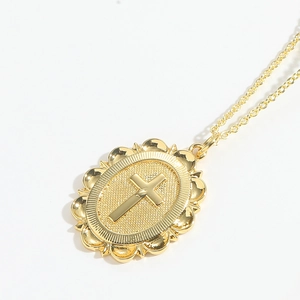 Close-up of golden oval vintage cross pendant necklace with decorative lace edges