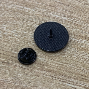 Black round Rocky Horror Picture Show badge with secure rubber clasp on wood