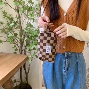 Détail d'une trousse à maquillage en velours côtelé à damier marron avec étiquette