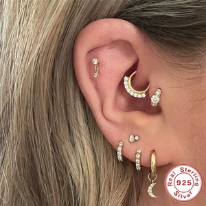 Gros plan sur des boucles d'oreilles lune en argent 925 et anneaux dorés au cartilage