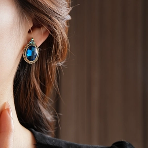 Gros plan d'une boucle d'oreille vintage avec une pierre ovale bleue et métal doré