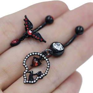 Λεπτομέρεια macro από gothic piercings αφαλού με μαύρο κρανίο και φτερωτό σταυρό