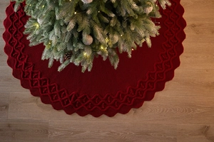 Dettaglio del tappeto per albero di Natale in maglia bordeaux con bordi ondulati su legno
