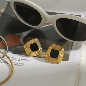 Detail of vintage square resin earrings in gold and black on a fashion magazine