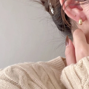 Elegant gold teardrop earrings in S925 sterling silver worn by a model in a cozy setting