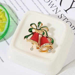 Close-up of double Christmas bell brooch with green bow and sparkling rhinestones