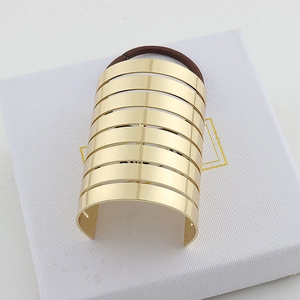 Detailed view of a wide gold metal striped ponytail cuff hair accessory on a white gift box