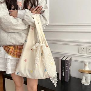 Detail of embroidered colorful bows on a cream canvas tote bag with lace bow accessory