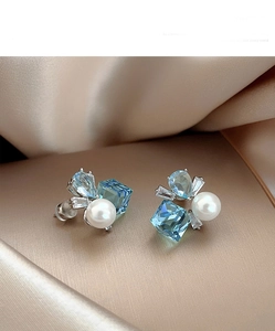 Macro detail of light blue faceted gems and pearls on champagne silk fabric background