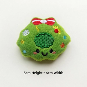 Detail of green embroidered plush charm with cartoon face and stars for DIY crafts