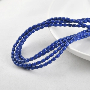 Detailed view of layered blue oval turquoise beads on a clean white ceramic plate