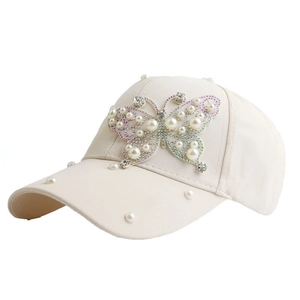 Detailed view of cream cotton baseball cap featuring pearl and rhinestone butterfly decor
