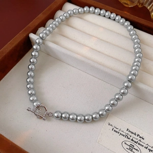 Detail view of gray pearl necklace with silver OT clasp in a luxury velvet jewelry tray