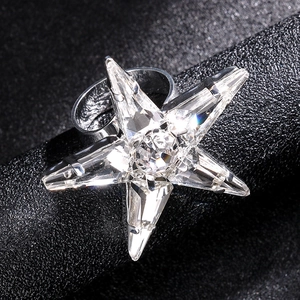 Elegant star-shaped crystal open ring with silver metal band on black texture background