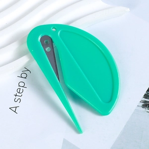 Macro view of a green leaf-shaped mini paper cutter and letter opener with metal blade