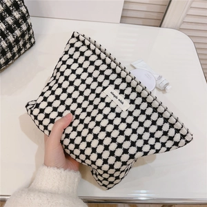 Détail d'une trousse à maquillage tissée à carreaux avec étiquette simple wish