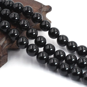 Close-up of polished black agate round beads with mirror finish on a vintage wooden base