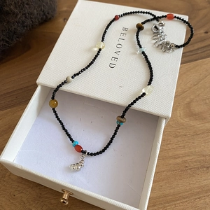 Detail of beaded natural stone necklace with metal pendant in a white jewelry gift box